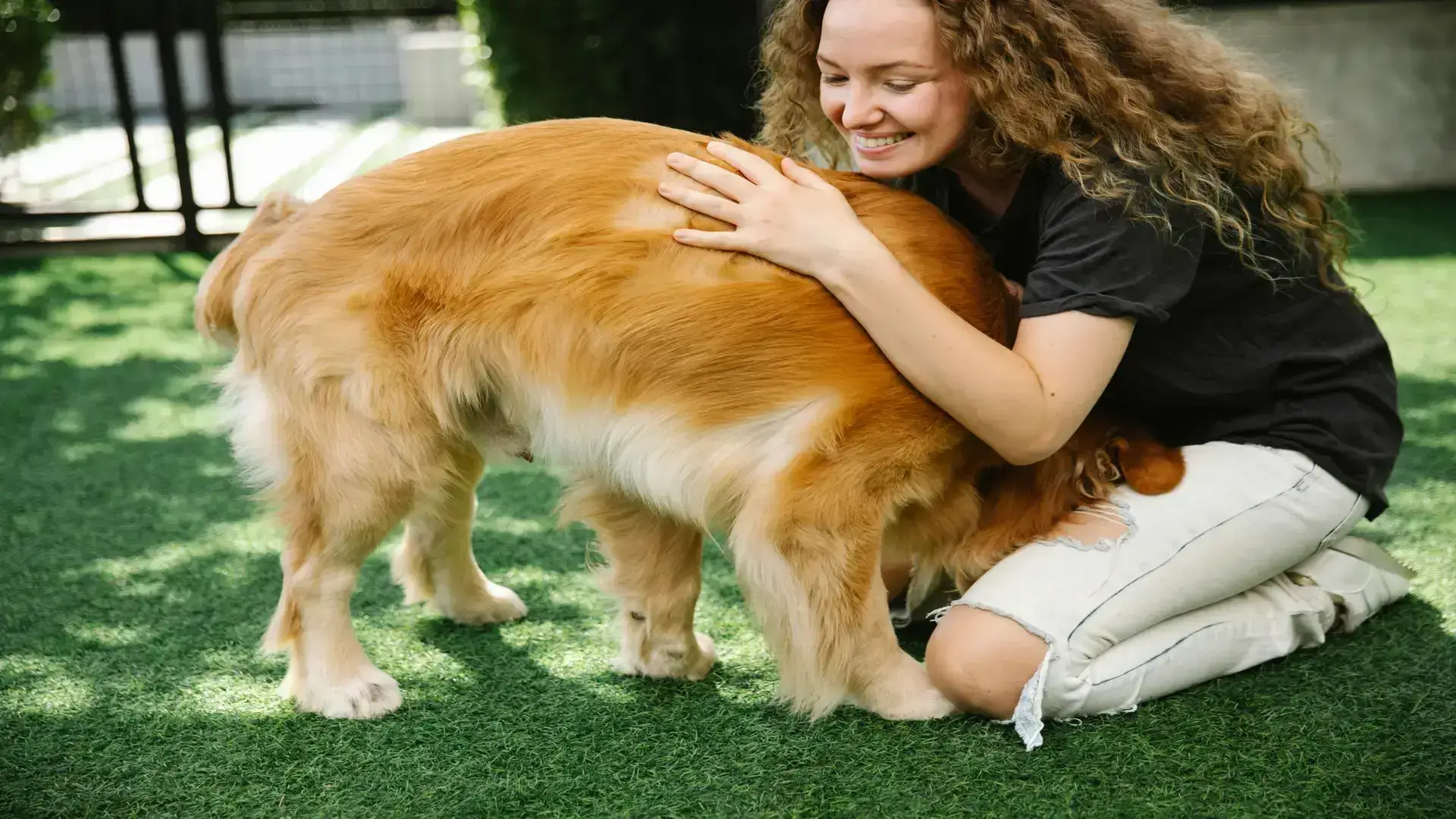 Smiling woman hugging a golden retriever in a grassy backyard, symbolizing The Scoop Ninjas’ welcoming, pet-loving community in Northeast Ohio.