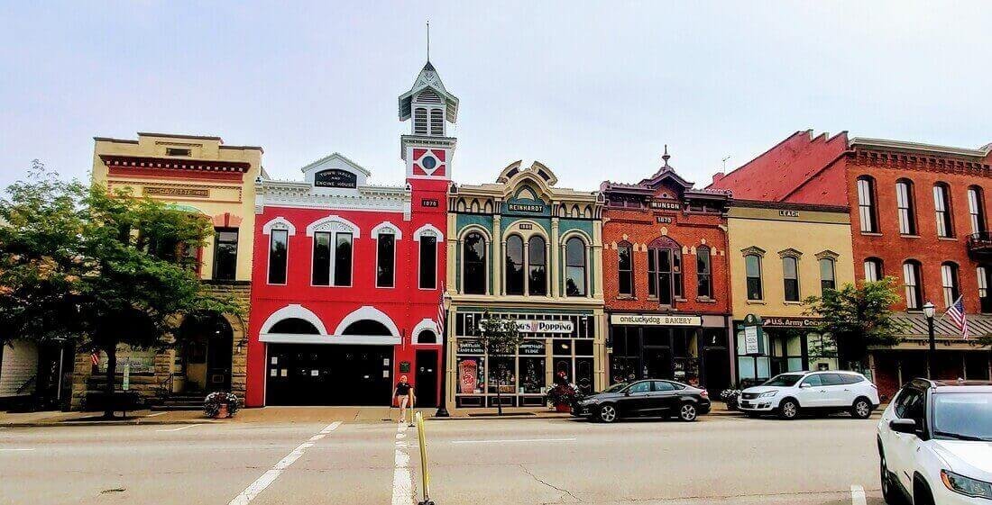 Historic downtown Medina, Ohio, featuring colorful 19th-century buildings, local shops, and a vintage red firehouse under a cloudy sky.