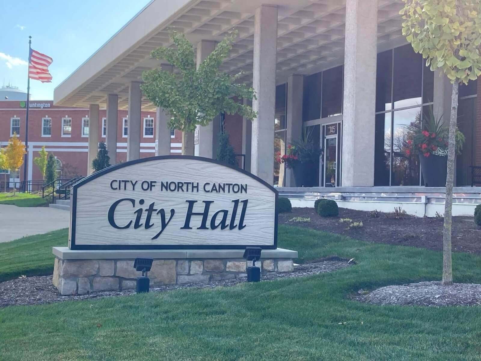City of North Canton City Hall sign in front of a modern government building with tall columns, landscaped greenery, and American flag in the background. One of the service areas for the Scoop Ninjas, a premier Pooper Scooper