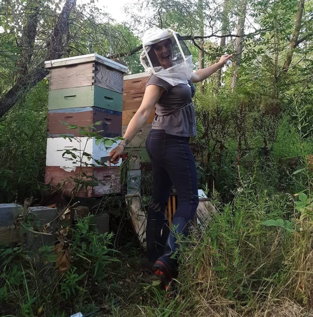 Beekeeper from Mueller Honey Bee Co. smiling beside vibrant bee hives, celebrating eco-friendly collaboration with The Scoop Ninjas to protect pollinators.